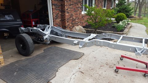 1994 Ford Bronco - Vehicle frame undergoing restoration work outside a garage.