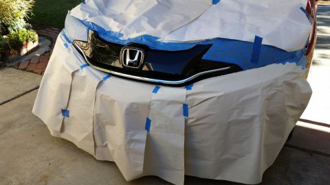 2015 Honda Fit - The front of a Honda is covered in paper and tape, likely for painting or repair.