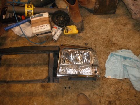 1995 Ford F-150 - A chrome headlight and black grille assembly are laid out on the floor, possibly for a vehicle repair or upgrade.