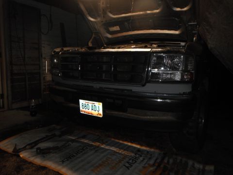 1995 Ford F-150 - The front of a 1995 Ford F-150 is visible with its hood open, revealing the grille and headlights.