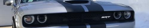 Silver Dodge Challenger SRT with black racing stripes on the hood and grille