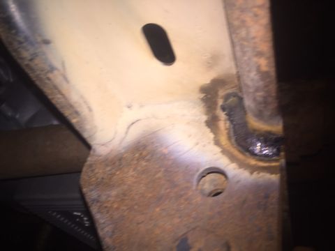 1982 Ford Bronco - Close-up view of a heavily rusted metal frame section, showing signs of welding and bolt holes.