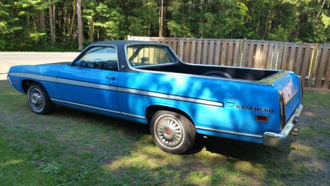 1971 Ford Ranchero - This blue pickup truck features a black vinyl roof and a chrome bumper. The 'RANCHERO' badging is visible on the rear fender.