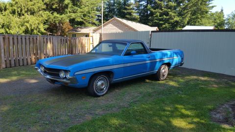 1971 Ford Ranchero - A blue 1970 Ford Ranchero is parked in a yard next to a fence and a building.