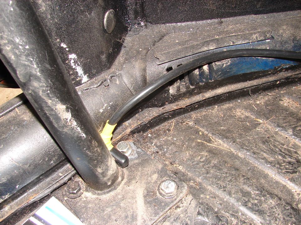 Close-up of a car's interior floor with a black tube and yellow tape