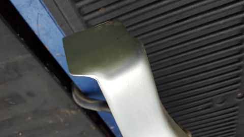 1994 Ford Bronco - Close-up view of a running board bracket, showing its mounting point on a textured surface.