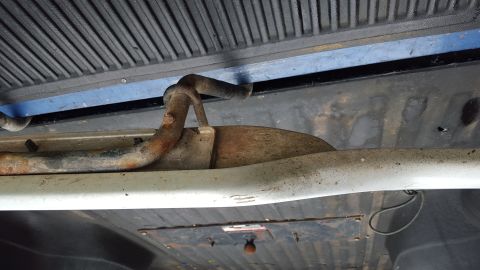 1994 Ford Bronco - Underside view of a vehicle's running board bracket, showing rust and wear.