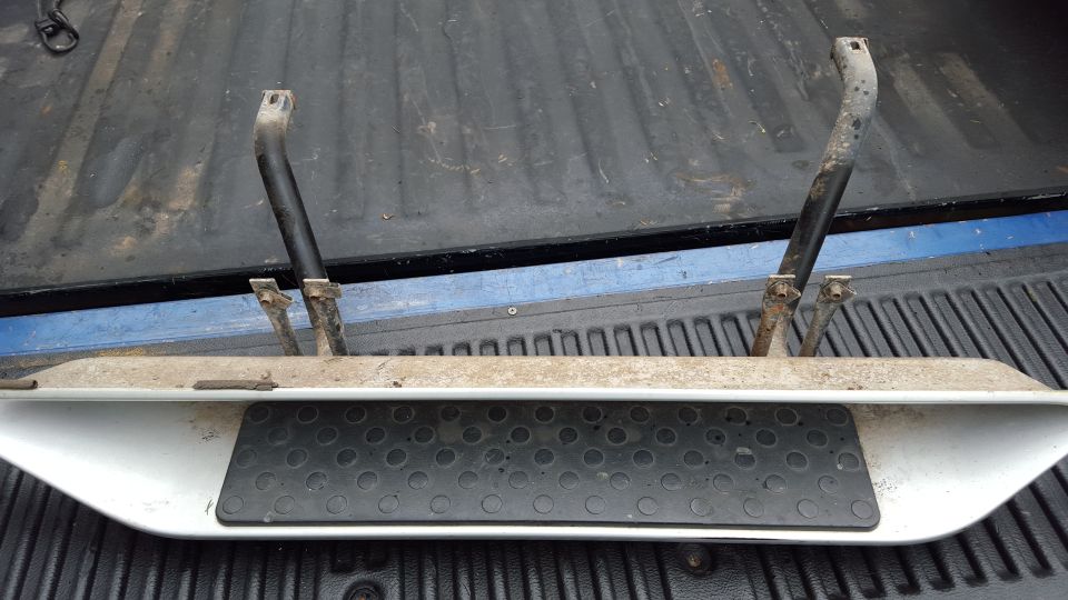 Running boards with black step pads, resting in the bed of a pickup truck