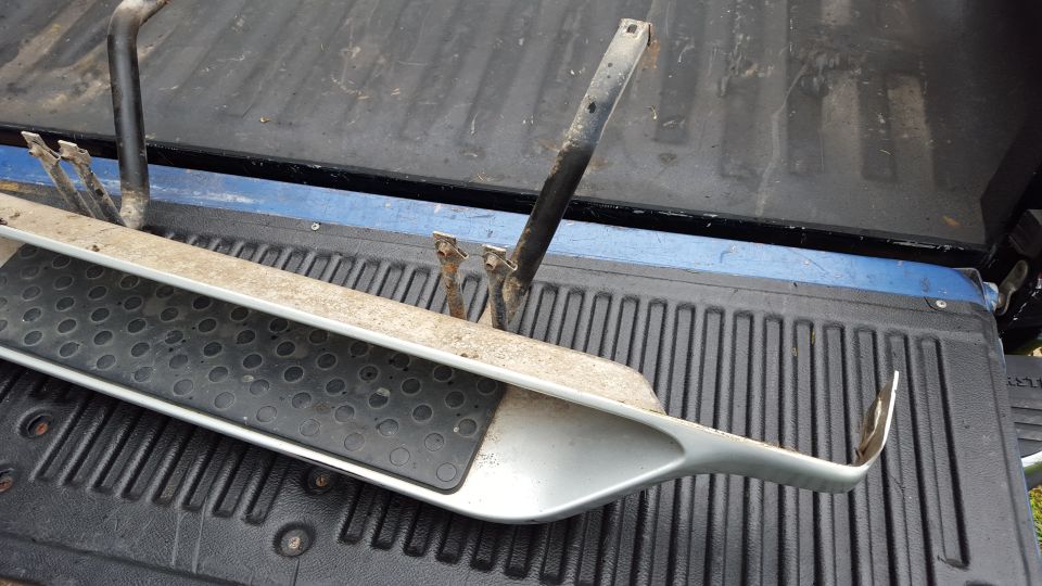 Running board with black textured grip and silver trim, resting in a truck bed