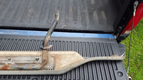 1994 Ford Bronco - A used running board is shown in the bed of a pickup truck, with a bent bracket attached.