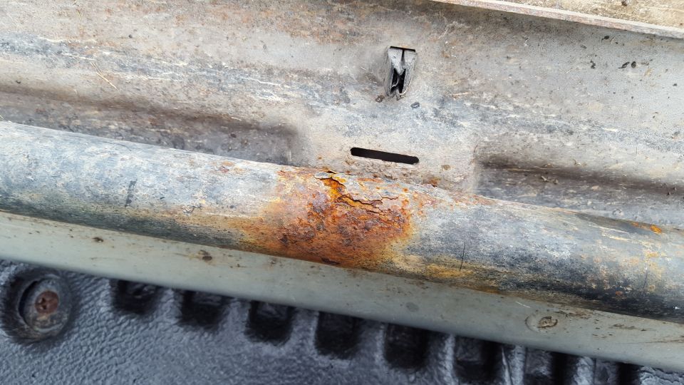 Rusted running board with mounting bracket and textured surface below