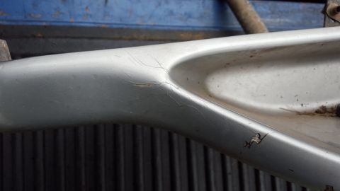 1994 Ford Bronco - Close-up of a damaged silver running board, showing surface imperfections and cracks.