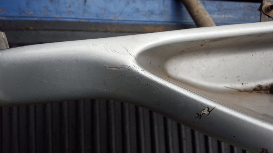 Silver running board with cracks and chips, viewed from the side