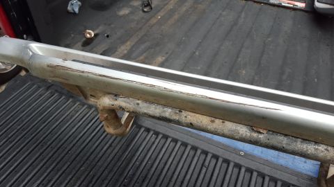1994 Ford Bronco - A close-up view of a silver running board and tow hitch, showing signs of wear and tear.