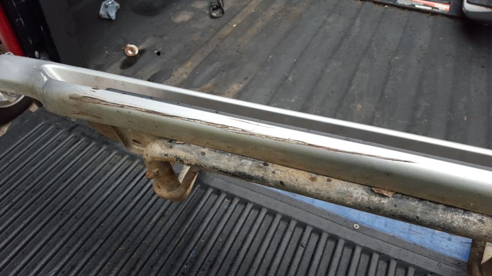 Silver running board with tow hitch, showing scratches and rust