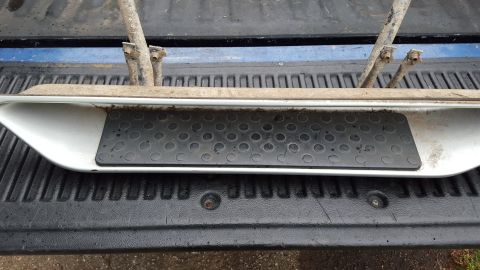 1994 Ford Bronco - A single running board with a textured grip pad is shown resting on the tailgate of a pickup truck.