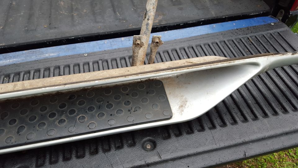 Silver running board with black textured grip pad, resting on a truck bed