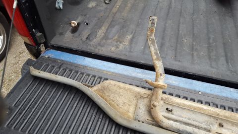 1994 Ford Bronco - A close-up view of a detached, weathered running board component resting in the bed of a pickup truck.