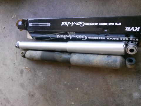 1996 Ford Bronco - Two KYB Gas-A-Just shock absorbers are shown next to an older, used shock absorber.