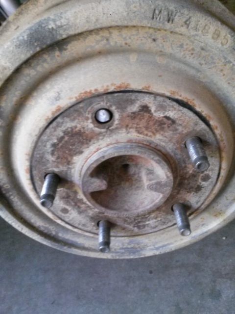 1996 Ford Bronco - Close-up of a rusty wheel hub assembly, showing lug bolts and a stamped part number.