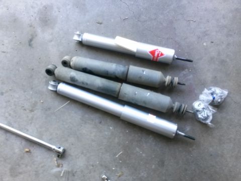 1996 Ford Bronco - Four shock absorbers are shown on a concrete floor, with a socket wrench nearby.