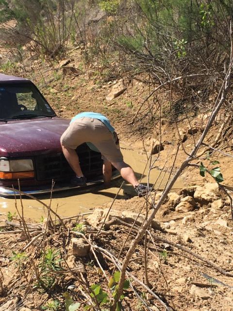 1996 Ford Bronco - A man attempts to free a maroon SUV stuck deep in muddy terrain.