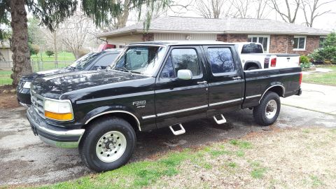1994 Ford Bronco - A black Ford F-250 Super Duty truck is parked in front of a house, with another vehicle beside it.