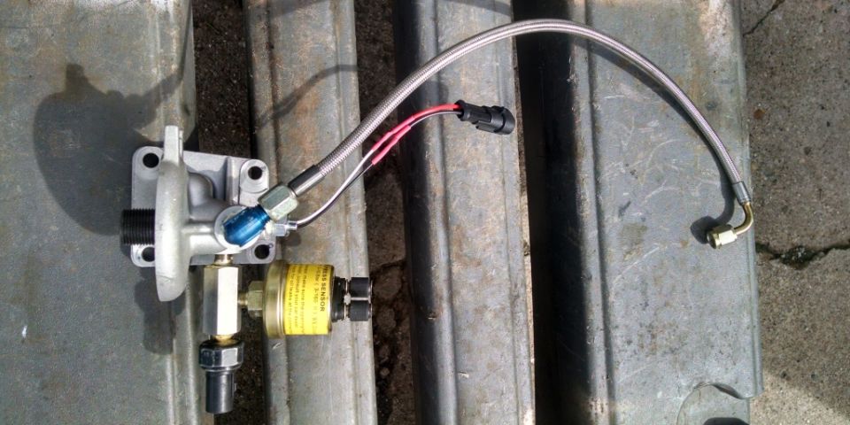 Fuel pressure regulator with braided line and sensor attached. Yellow sensor has text on it