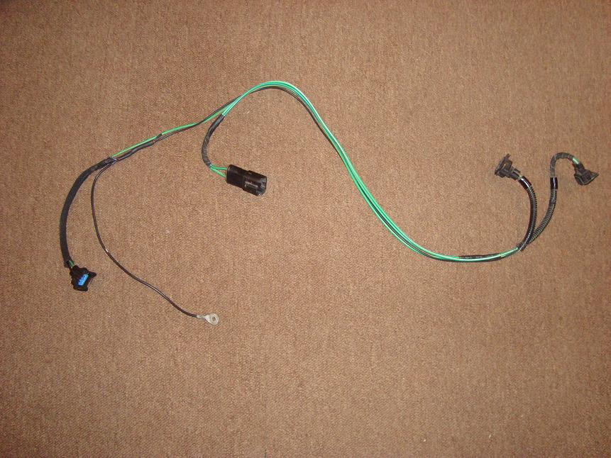 Green and black automotive wiring harness with connectors on carpet