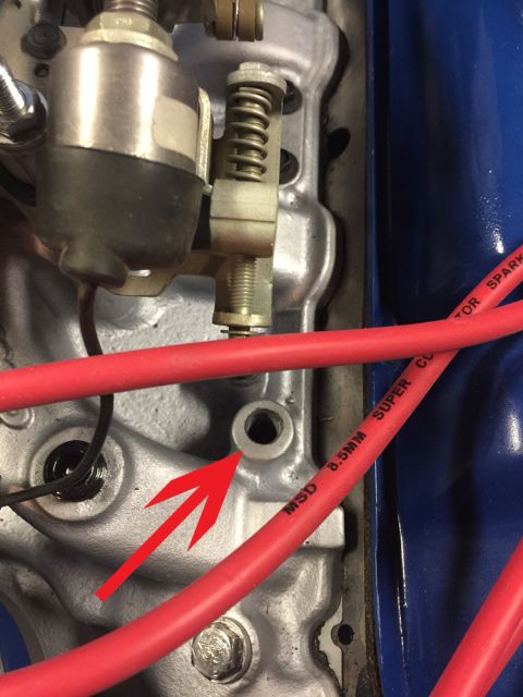 1978 Ford Bronco - A red arrow highlights a hole on a metallic engine component, with red spark plug wires in view.