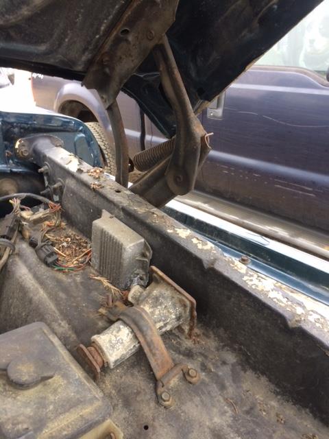 1979 Ford F-150 - The engine bay of a truck shows rust and wear, with another vehicle visible behind it.