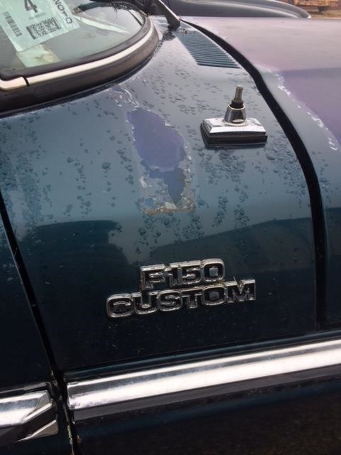 1979 Ford F-150 - Close-up of a dark green Ford F-150 Custom fender, showing peeling paint and chrome badging.