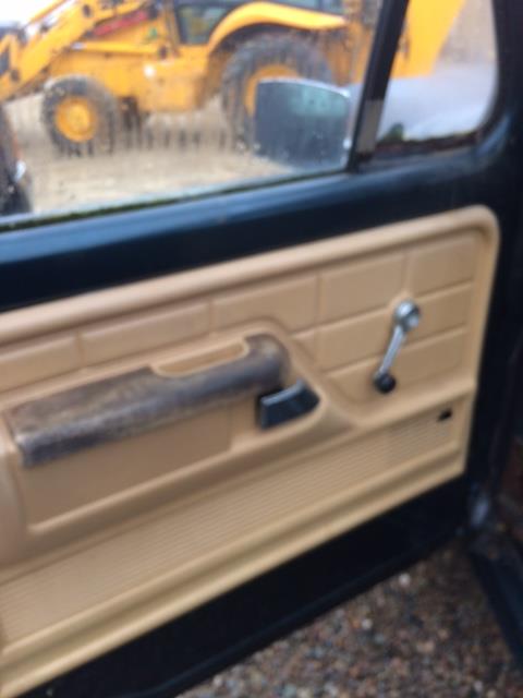 1979 Ford F-150 - Interior view of a 1979 Ford F-150 with a tan door panel, reflecting a yellow backhoe in the side mirror.
