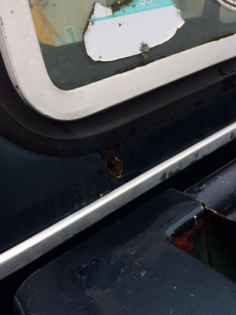 1979 Ford F-150 - A detail shot of a truck's bodywork reveals rust spots and a partial sticker on the window frame.