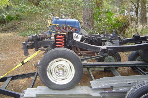 1974 Ford Bronco - The front end of a vehicle, including the engine and suspension, is shown on a trailer outdoors.