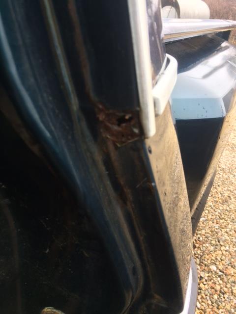 1979 Ford F-150 - Close-up view of rust forming on the door frame of a dark blue vehicle, with a portion of the bed visible.