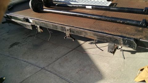 2016 Ford F-250 - Two trailer axles and their wheels are positioned on a flatbed trailer.