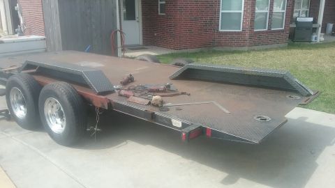 2016 Ford F-250 - A car hauler trailer is parked on a concrete driveway in front of a brick house.