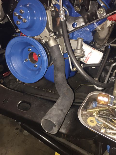 1978 Ford Bronco - Close-up view of an engine bay blue painted components and a black radiator hose, with a tray of hardware in the foreground.
