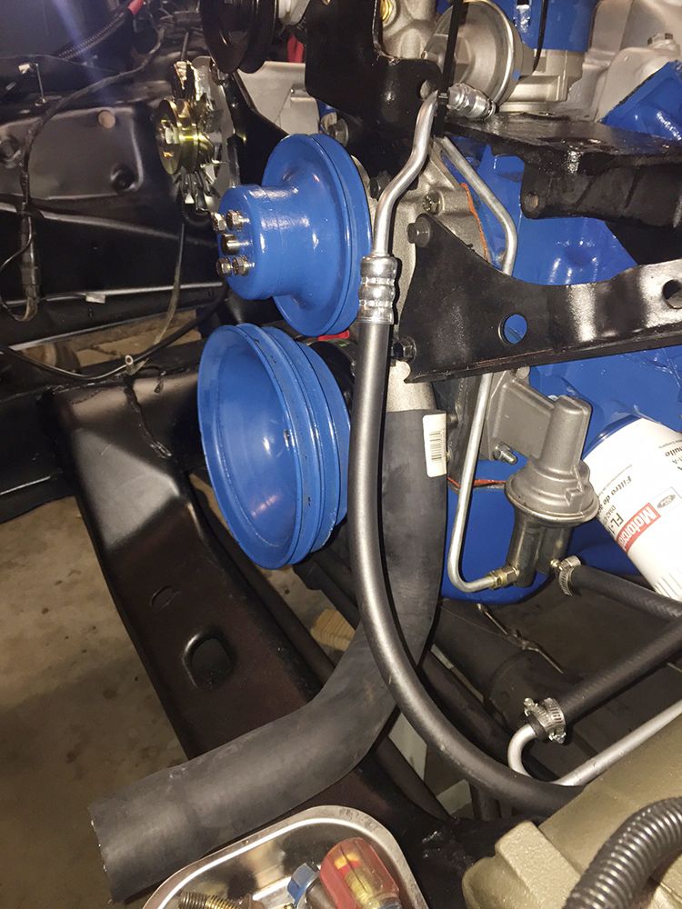 Close-up of blue painted engine pulleys and fuel pump assembly