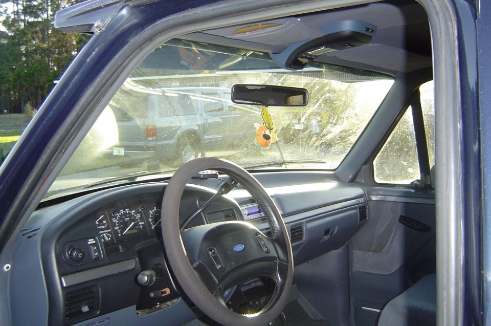 Gray dash and Ford airbag steering wheel of a dark blue Bronco seen through the open driver door