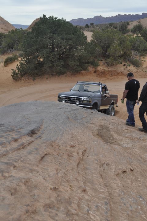 1991 Ford Bronco - A Ford F-series truck navigates a rocky off-road trail under a cloudy sky.