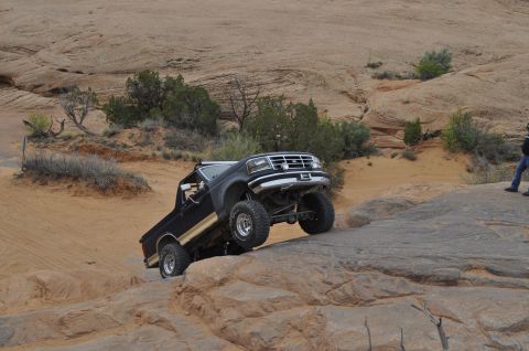 1991 Ford Bronco - A black Ford Bronco navigates a challenging rocky terrain in a desert landscape.