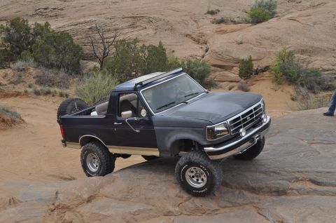 1991 Ford Bronco - This Ford Bronco is navigating a rocky trail in a desert landscape.