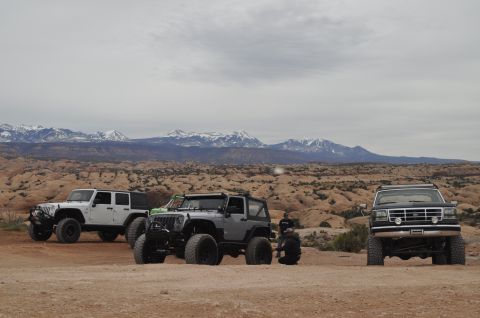 1991 Ford Bronco - A 1991 Ford Bronco is parked in a desert landscape with two Jeeps nearby under a cloudy sky.
