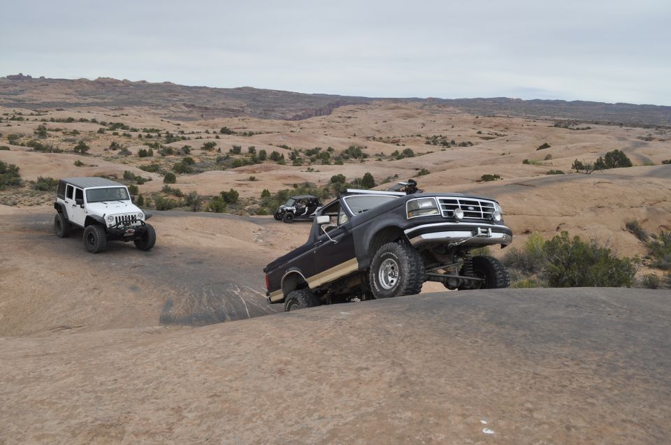Black Ford Bronco and white Jeep off-roading on rocky desert terrain