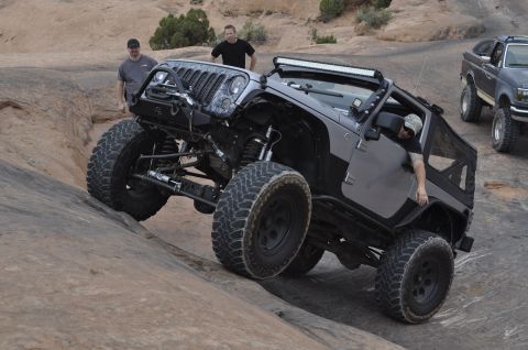 1991 Ford Bronco - A modified Jeep Wrangler navigates a rocky incline, with another vehicle visible in the background.