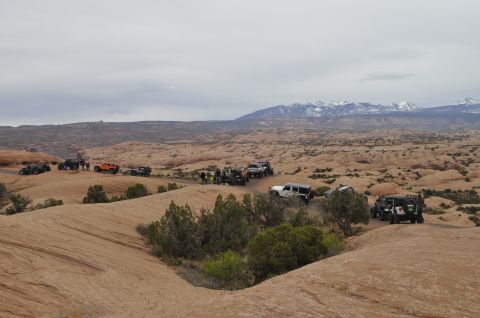 1991 Ford Bronco - A group of off-road vehicles navigates a desert trail under a cloudy sky.