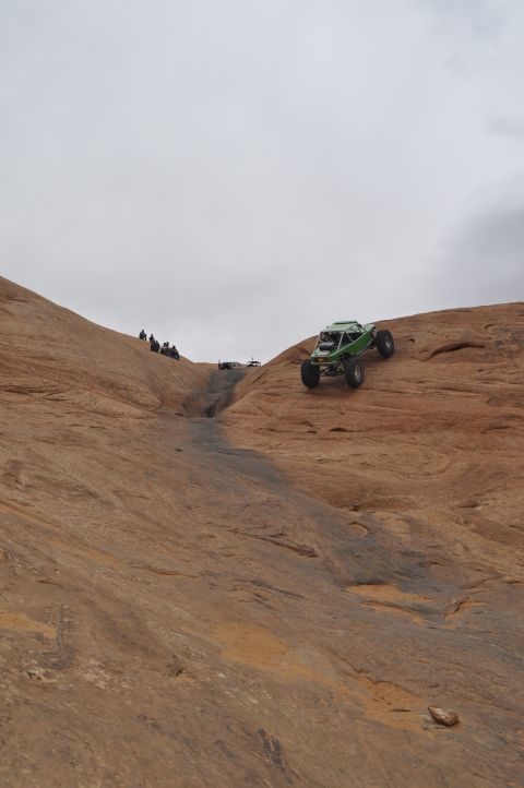 1991 Ford Bronco - A custom off-road buggy navigates a steep, rocky terrain with a group of onlookers observing the climb.