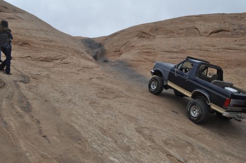 1991 Ford Bronco - Ford Bronco navigates a challenging off-road trail in a desert landscape.